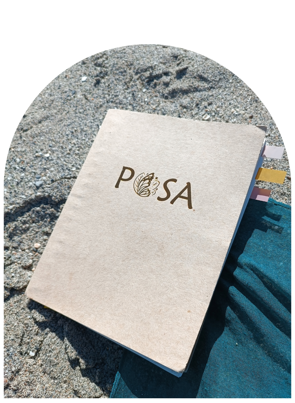 A copy of Shayna's Posa Journal on a sandy beach.